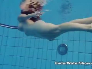 Redheaded belleza nadando desnuda en la piscina
